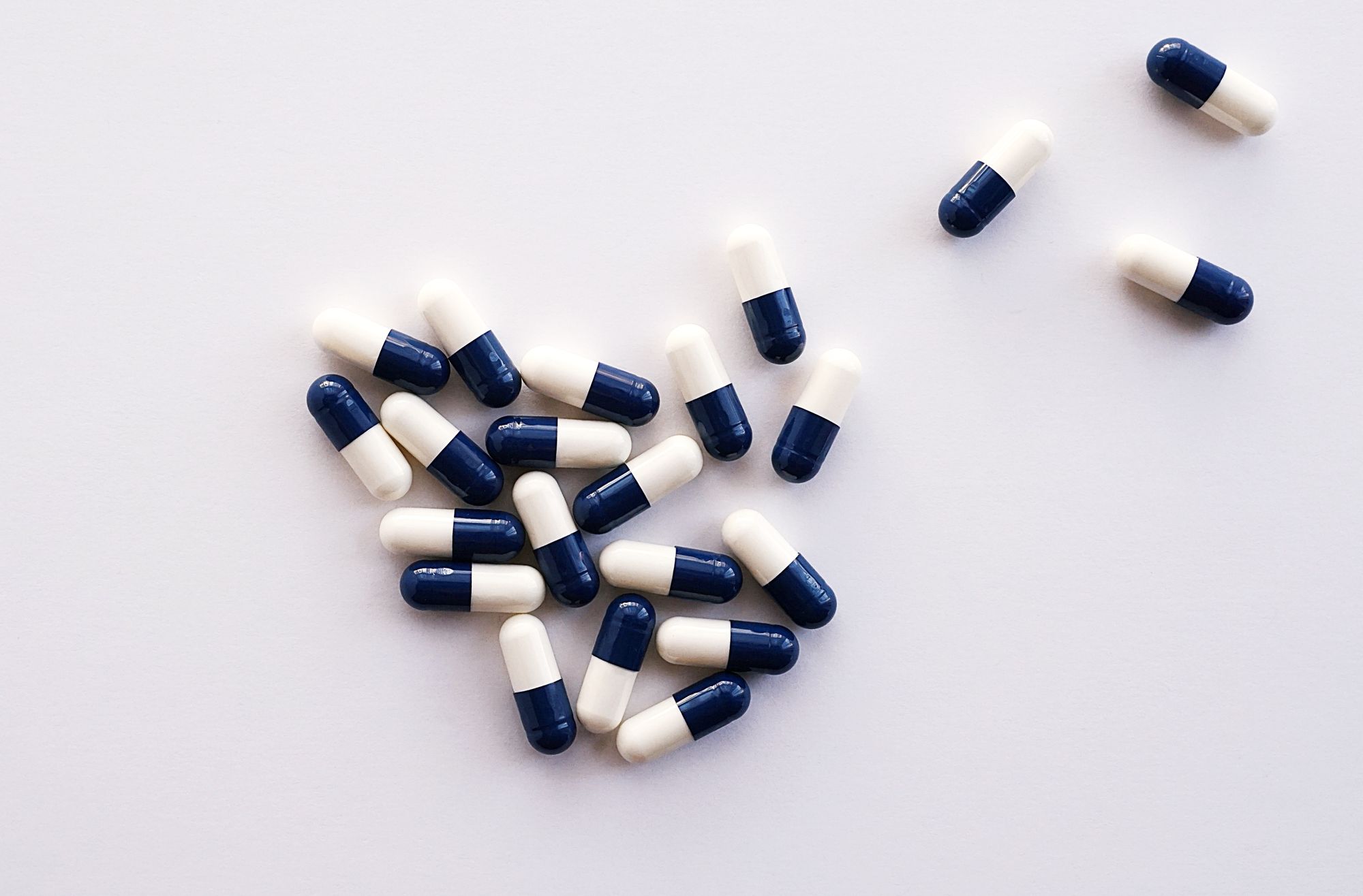 Blue and white capsules on a white surface